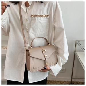 Schicke beige Umhängetasche mit Griff und Metallschnalle getragen von einem Modell