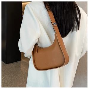 Brown leather crescent shoulder bag with white blazer shown from a side view on a model