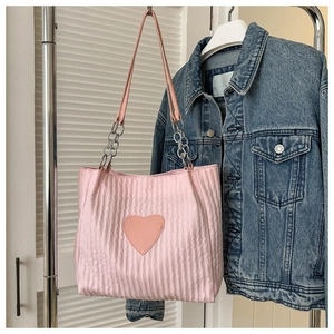 Detalle del bolso tote rosa con parche de corazón de cuero y cadena metálica