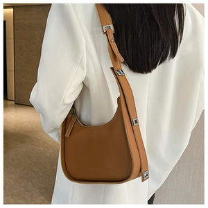 Close-up of brown crescent shoulder bag with lychee texture and silver buckle detail