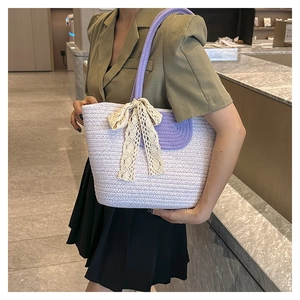 Detailed view of woven straw tote bag with lilac accents and beige lace bow detail