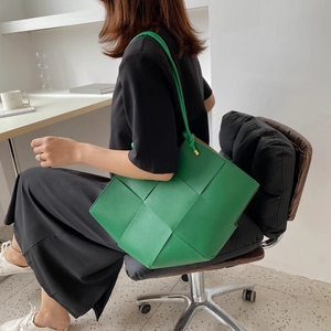 Green oversized woven leather tote bag with wide checkerboard pattern and knotted shoulder strap