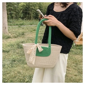 Detail of hand-woven straw tote with green handles and white lace bow decoration