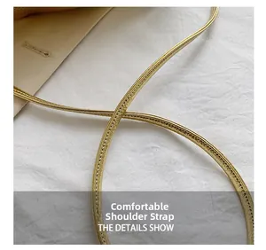 Detail of comfortable thin shoulder strap on a gold faux leather handbag with stitching
