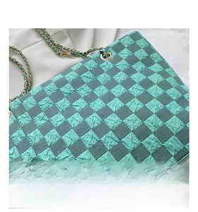 Close-up of green checkered tote bag showing quilted texture and metal chain strap