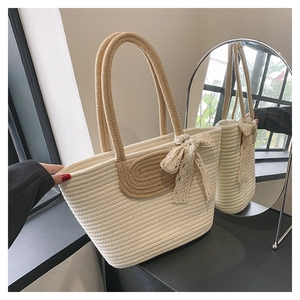 Detail of hand-woven cream tote bag with light brown handles and a lace bow accent