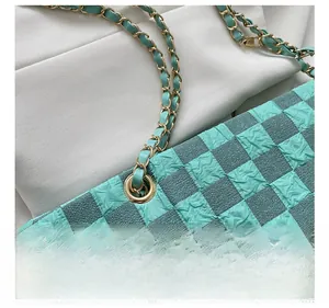 Detail of green checkerboard shoulder bag showing textured fabric and gold metal chain strap