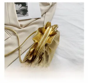 Detail of a gold metallic ruched handbag on a beige coat with a luxury fashion magazine