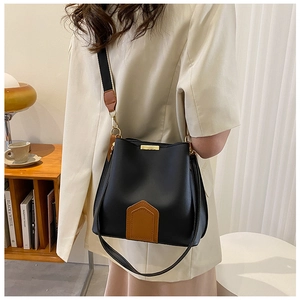 Detail der schwarz-braunen Eimertasche mit breitem Gurt und goldener Hardware