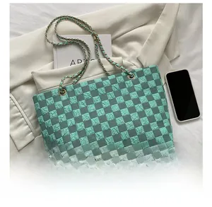 Detail of green checkerboard tote bag with pleated texture and gold chain strap