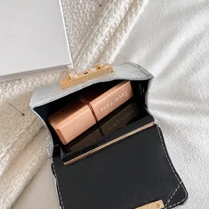 Interior storage space of silver croc-effect mini bag with lipstick and powder