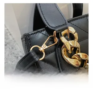 Détail du cuir matelassé noir avec crochet en métal doré et chaîne épaisse brillante