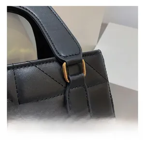 Détails de l'anneau en D doré sur le cuir noir matelassé de ce sac à main