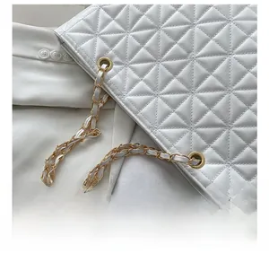 Detail of white quilted tote bag featuring premium stitching and gold chain strap