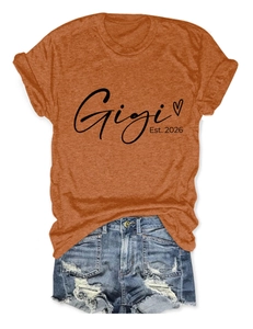 Détail de l'imprimé Gigi Est 2026 sur un T-shirt orange avec un short en denim bleu