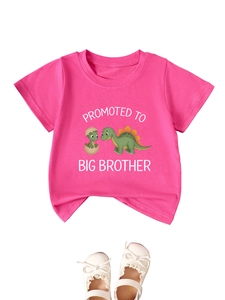 Close-up of rose pink Big Brother t-shirt with cute dinosaur print and white bow shoes