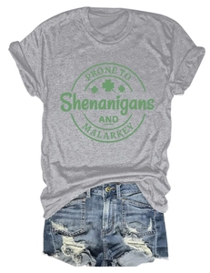 Flat lay of gray T-shirt with green clover print and distressed denim shorts outfit