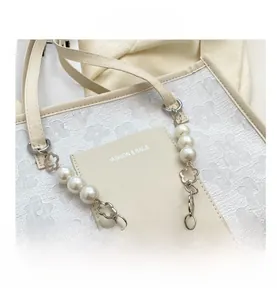Detail of 3D floral embossed fabric on cream shoulder bag with pearl and metal chain