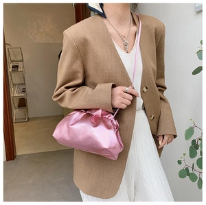 Dettaglio borsa a sacchetto rosa metallizzato plissettata indossata come borsa a tracolla