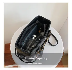 Vue intérieure d'un sac à bandoulière matelassé noir contenant téléphone et parfum