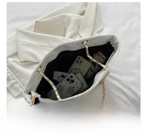 Detail showing spacious interior of white quilted tote bag with chain strap and items