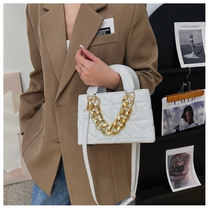 Détail d'un sac à main blanc matelassé avec chaîne dorée et poignée en cuir