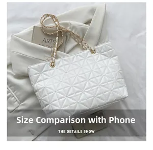 Detailed view of white quilted PU leather tote bag next to a mobile phone for size comparison