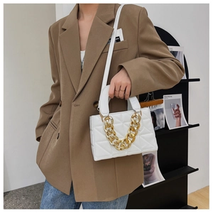 Détail d'un sac à bandoulière matelassé blanc avec une poignée à grosse chaîne dorée