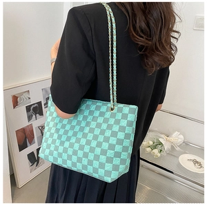 Detail of blue checkerboard tote bag with stylish gold metal chain shoulder strap