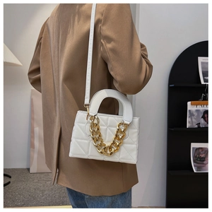 Détail d'un sac blanc matelassé avec chaîne dorée porté par un mannequin en blazer