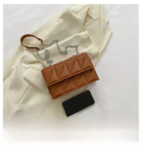 Brown quilted crossbody bag with silver chain strap shown next to a smartphone for scale
