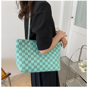 Close-up of mint green checkered tote bag with wrinkled texture and chain strap