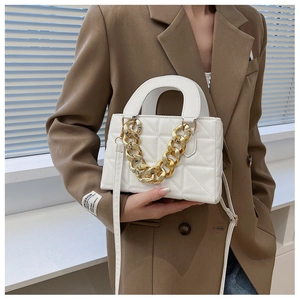 Détail d'un sac blanc matelassé avec une chaîne dorée épaisse et bandoulière en cuir
