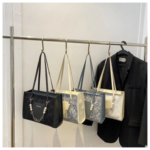 Detail view of four colorful textured handbags with star pearl chains on a rack