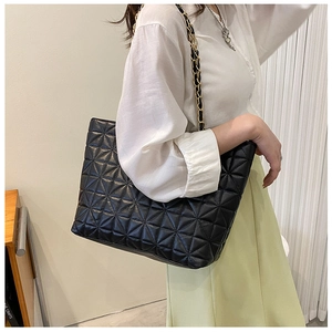Detail view of the black quilted tote bag with triangle stitching and metal chain strap