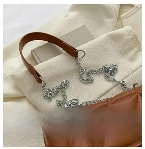Detail of brown quilted faux leather bag with silver chain strap and leather handle