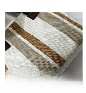 Close-up of striped canvas tote bag showing weave texture and leather strap attachment