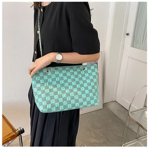 Detail of mint green checkerboard tote bag with woven metal chain strap on shoulder