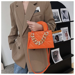 Détail du sac orange à carreaux avec grosse chaîne dorée et texture en cuir lisse