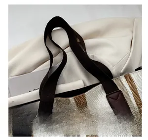 Close-up of striped canvas tote bag with reinforced leather patches and heavy-duty handles