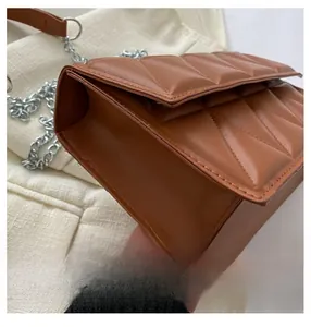 Detail view of brown quilted crossbody bag with metal chain and accordion fold structure