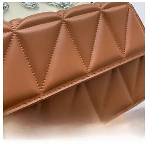 Close-up of caramel brown crossbody bag featuring geometric triangular quilting and silver chain