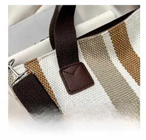 Detailed close-up of striped canvas tote showing reinforced stitching and metal hardware