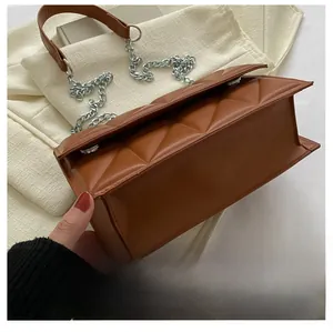 Detail view of brown quilted faux leather crossbody bag with silver chain strap