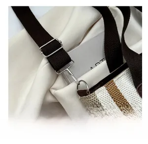 Detailed macro view of silver metal hooks and brown nylon strap on a striped tote bag