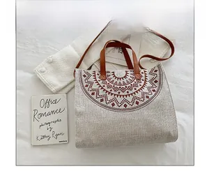 Detail of beige canvas tote with brown geometric print and leather handles on soft fabric
