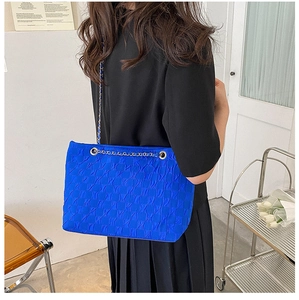 Detail of royal blue tote bag featuring pleated texture fabric and silver metal chain strap