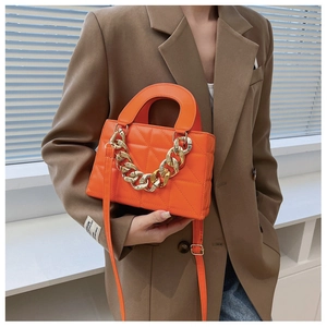 Détail du sac à main orange matelassé avec chaîne dorée et poignée supérieure chic