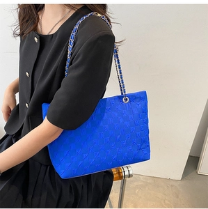 Detail of royal blue quilted tote bag with golden metal chain shoulder straps