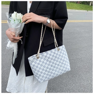 Close-up of woven gray and white checkered pattern on a chain shoulder tote bag